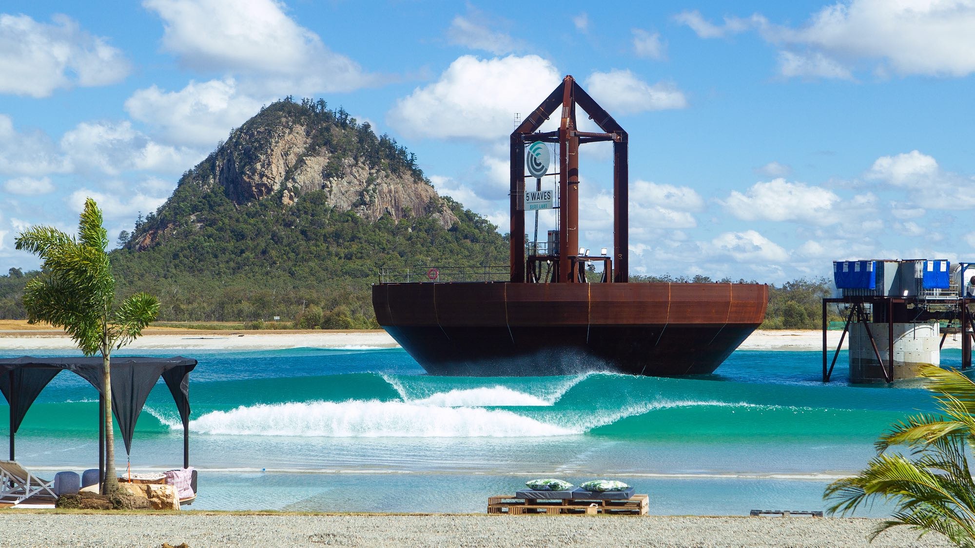 wave pool travel: Image shows giant wave pool plunger and mountain backdrop at Surf lakes in Yeppoon Australia